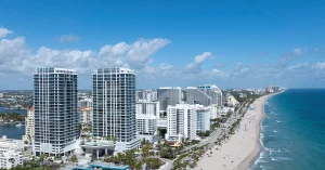 Aerial view of luxury oceanfront condo towers along Fort Lauderdale Beach and Atlantic shoreline.