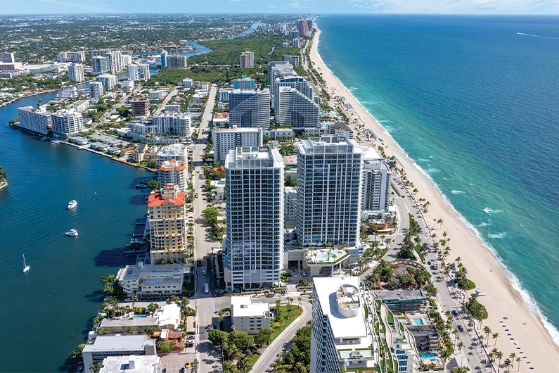 Aerial view of coastal city with high-rise condos, beach, and ocean