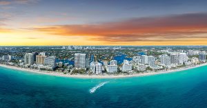 Wide aerial view of coastal skyline at sunset with ocean and beachfront buildings