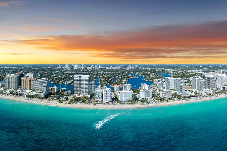Wide aerial view of coastal skyline at sunset with ocean and beachfront buildings